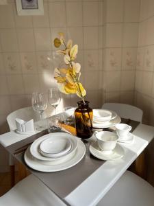 a table with white plates and a vase with yellow flowers at Arena1 in Mar del Plata