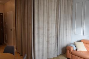 a living room with a couch and curtains at Warsaw City Break II in Pruszków