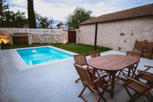 un patio con mesa y sillas y una piscina en Casas Las Hazas, en La Cuesta
