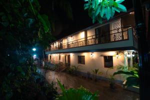 un edificio con balcón por la noche en KINGMAKER'S Plantation with River Stream en Madikeri