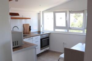 a kitchen with white cabinets and a sink and two windows at Apartmani Adi Tkon in Tkon +22 photos