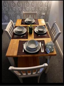 a wooden table with plates and utensils on it at Charming 3-Bed House in Gloucester in Gloucester