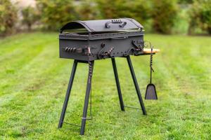 a grill sitting on a tripod in the grass at 4 Bedroom House with Playground, BBQ & Free Parking in Rīga