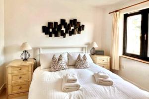 una camera da letto con un letto bianco con due asciugamani di Central Spacious Ground Floor Flat with Courtyard a Kingsbridge