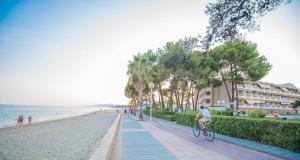 a man riding a bike down a sidewalk next to the beach at Ona Internacional Apartments in Cambrils