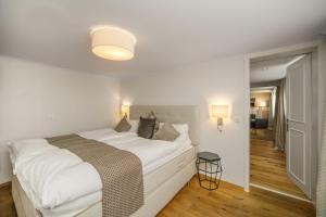 a white bedroom with a large bed and a hallway at Boutique Hotel Moosegg in Emmenmatt