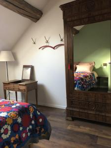 een slaapkamer met een spiegel, een bed en een bureau bij La Petite Maison in Auxey-Duresses
