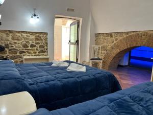 um quarto com uma cama azul e uma parede de pedra em B&B Centro Storico em Caltanissetta