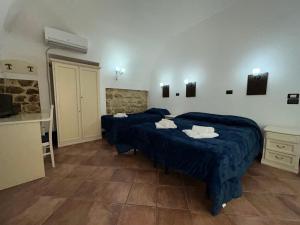 two beds in a room with blue comforters at B&B Centro Storico in Caltanissetta