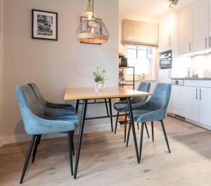 a dining room table with blue chairs in a kitchen at Strandgut Wohnung 4 in Wenningstedt