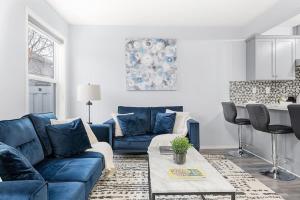 a living room with a blue couch and a table at Large Townhome Near Anthony Henday in Ellerslie with Driveway & Visitor Parking, King Bed, 4 Queen Beds, Fully Equipped Kitchen & More! in Edmonton