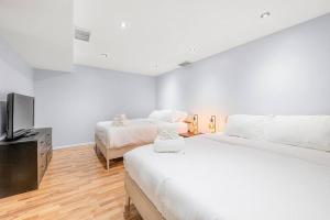 a bedroom with two beds and a flat screen tv at Large Townhome Near Anthony Henday in Ellerslie with Driveway & Visitor Parking, King Bed, 4 Queen Beds, Fully Equipped Kitchen & More! in Edmonton