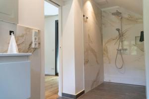 y baño con ducha y paredes de mármol. en Chalet Schmelz Huette mit Sauna und Garten en Flattach