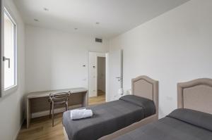 1 Schlafzimmer mit 2 Betten, einem Schreibtisch und einem Stuhl in der Unterkunft Diana - Sirio- Aura Montegrotto Terme Lovely Apartments! in Montegrotto Terme