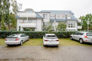 3 voitures garées sur un parking devant une maison dans l'établissement Modernes Apartment in Potsdam-Golm - 2 Zimmer - Balkon - Beamer - Disney Plus, à Potsdam