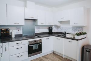 a white kitchen with white cabinets and a stove at Deluxe 2 Bed Flat in Patchway near Aztec West and Cribbs Causeway Bristol in Bristol