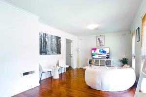 a living room with a white couch and a table at Mel Eastern Villa near everything in Doncaster East