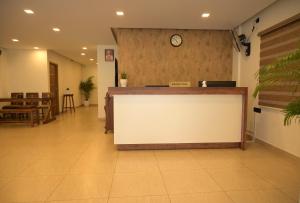 a reception desk in a lobby with a clock on a wall at JAY KAY RESIDENCY in Ernakulam