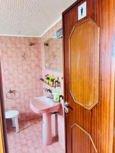 baño con lavabo rosa y puerta de madera en G & S - Hostel Vila do Conde, en Gião