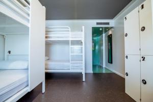 Habitación con literas blancas y pasillo. en AMISTAT Island Hostel Ibiza - ALBERGUE JUVENIL, en San Antonio