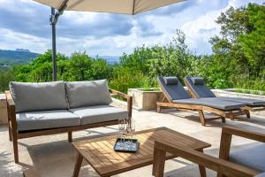 eine Terrasse mit 2 Liegestühlen und einem Sonnenschirm in der Unterkunft Esprit du Sud Les 4 Mousquetaires in Roquebrune-sur-Argens