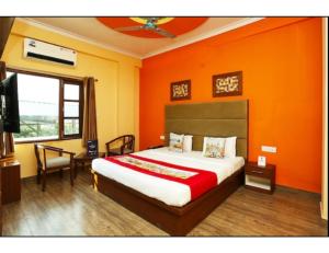 a bedroom with a bed with an orange wall at Hotel Kolam, Dehradun in Dehradun