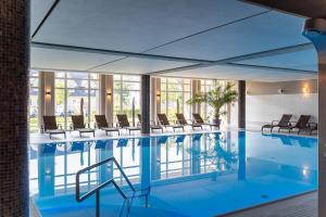 a pool in a hotel with chairs and tables at StrandResort Markgrafenheide in Warnemünde