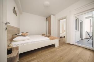 a white bedroom with a bed and a chair at Apartment Stefanio in Vodice