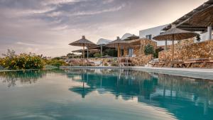 a swimming pool with umbrellas and tables and chairs at YPSELI Anafi's hive in Anafi