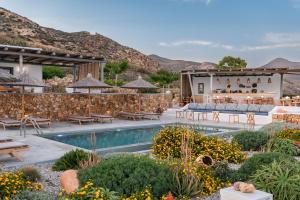 a resort with a pool and a restaurant with mountains in the background at YPSELI Anafi's hive in Anafi