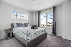 1 dormitorio con cama y ventana en New Cozy Family Townhome Sleeps 10 Comfortably w Banff Pass, en Airdrie