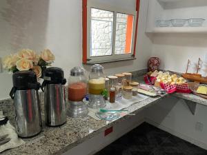 - un comptoir de cuisine avec des bouteilles de jus et d'autres ingrédients dans l'établissement Pousada Itaúnas, à Conceição da Barra