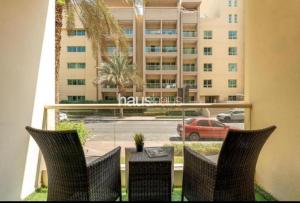 a balcony with a table and chairs and a building at Phineek Studio Apartment The Green Al Alka in Dubai