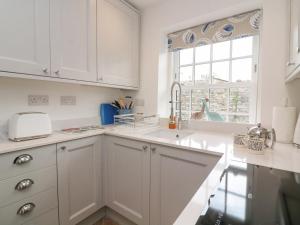 a white kitchen with a sink and a window at Quay Cottage in Salcombe