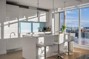 una cocina con armarios blancos y una barra con sillas en Downtown Luxurious Apartment with Parking and Gym en Calgary