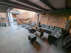 patio con sofá, mesas y pared de ladrillo en Havel Suites, en Havelberg