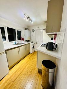 a kitchen with white appliances and a wooden floor at Cosy 3 Bed House - Reading Cent. Free Parking in Reading