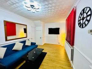 uma sala de estar com um sofá azul e uma televisão em Cosy 3 Bed House - Reading Cent. Free Parking em Reading
