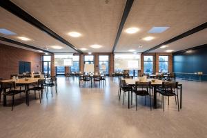 a dining room with tables and chairs and windows at Sportium Sportel in Varde