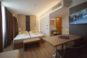 リーヴァ・デル・ガルダにあるAmbassador Suite Hotelのベッド2台とテーブルが備わるホテルルームです。
