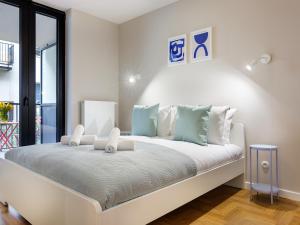 a white bedroom with a large white bed with blue pillows at Tyzenhauz Apartments Vistula with Parking in Krakow