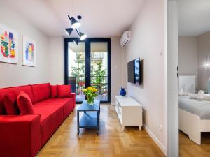 a living room with a red couch and a bed at Tyzenhauz Apartments Vistula with Parking in Krakow