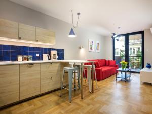 a kitchen and living room with a red couch at Tyzenhauz Apartments Vistula with Parking in Krakow