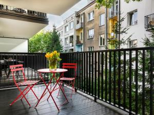 a table and chairs on a balcony with a vase of flowers at Tyzenhauz Apartments Vistula with Parking in Krakow