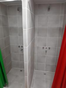 y baño con ducha y azulejos blancos. en Hostel Cruz del Sur en Ushuaia