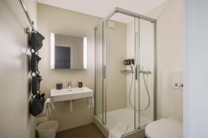 a bathroom with a glass shower and a sink at Boutique Hotel Moosegg in Emmenmatt