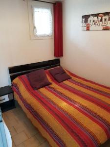 ein Schlafzimmer mit einem Bett mit einer bunten gestreiften Decke in der Unterkunft T3 70 m2 standing Cap d'Agde 4-6 pers in Cap d'Agde