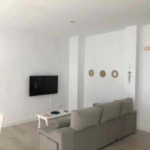 ein Wohnzimmer mit einem Sofa und einem TV an der Wand in der Unterkunft Apartamento 8 mamia costa in Torreguadiaro