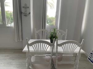 einen weißen Esstisch mit 2 Stühlen und einer Pflanze in der Unterkunft Apartamento 8 mamia costa in Torreguadiaro