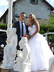 Una novia y un novio posando frente a una estatua en Gîte Au Clair Matin ,la Mure, les passerelles Monteynard, en Pierre-Châtel